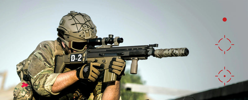 Person in military gear holding a rifle with a scope against a clear sky. reticle of red dot sight