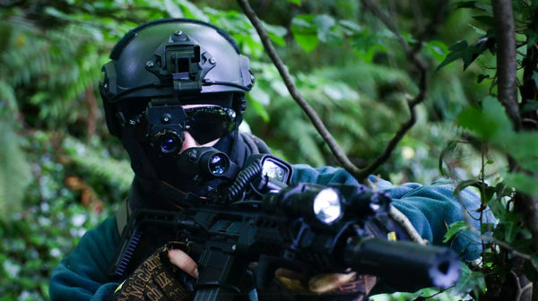 Person in tactical gear with a rifle in a forest setting