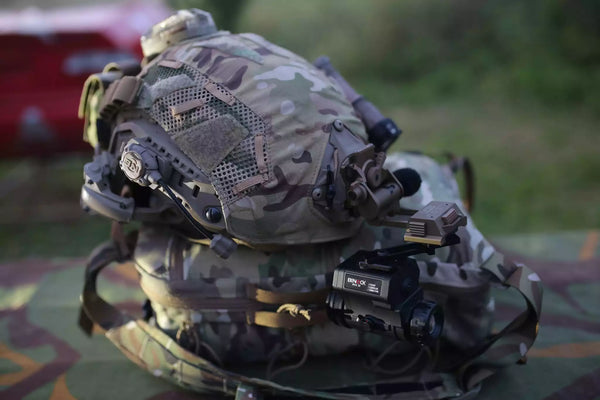 Camouflage helmet with electronic equipment on a grassy background