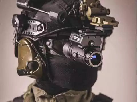 Person wearing a helmet with various electronic night vision devices on a plain background
